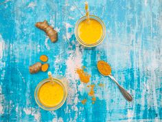 three jars filled with yellow liquid next to two spoons and some turment