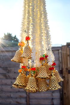 a bunch of bells that are hanging from a tree in front of a wooden fence