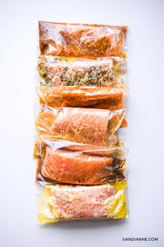 salmon fillets wrapped in cellophane on top of each other with seasoning