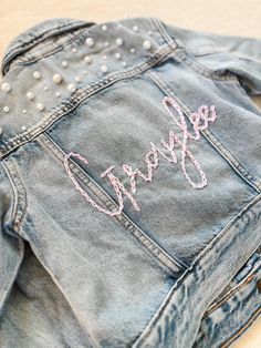 PERSONALIZED BABY, TODDLER & KID'S JEAN JACKET    These customizable jean jackets are perfect for the little princess in your life and make great gifts, too! The lettering is hand-embroidered and unique to each jacket. These are so unique and adorable, no two designs are the same! Want pearls added to yours? Drop that in the notes! Cold-wash delicate and hang-to-dry for longevity.    SHIPPING:    As this product is made to order, the current turnaround time is 1-3 weeks.   LOCAL PICKUP:    For l Customizable Denim Outerwear For Spring, Customizable Denim Jacket For Spring, Spring Customizable Denim Jacket, Cute Fitted Embroidered Outerwear, Cute Fitted Denim Jacket With Pockets, Customizable Blue Denim Jacket For Spring, Customizable Spring Denim Jacket, Casual Pink Embroidered Denim Jacket, Customizable Long Sleeve Denim Jacket For Spring