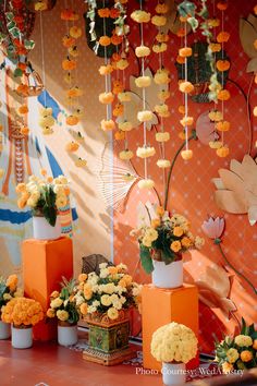 orange and white flowers are in vases next to each other on a red table