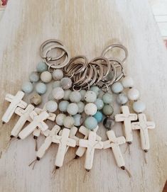 a bunch of beads and cross charms on a wooden table next to a pair of scissors