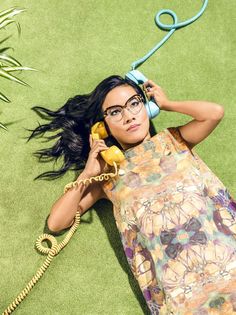 a woman laying on the ground with a phone to her ear and holding a banana