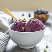 two scoops of blueberry ice cream in a white bowl