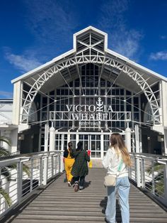 two women walking across a wooden bridge to the victoria and william museum in vancouver, canada