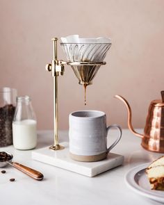 a coffee maker sitting on top of a counter next to some cups and spoons