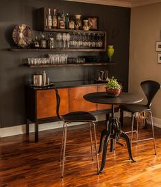 a small table with two chairs in front of a shelf filled with bottles and glasses