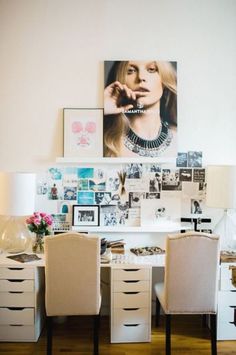 a white desk topped with lots of pictures and chairs next to a lamp on top of a table