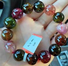 a hand holding a bracelet made out of multicolored glass beads with a price tag on it