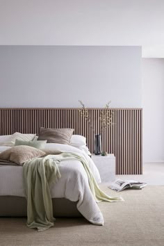 a large bed sitting next to a tall wooden headboard in a room with white walls