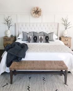 a white bed with pillows and blankets on top of it next to two nightstands