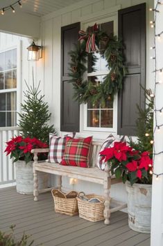 a porch decorated for christmas with wreaths and poinsettis on the bench