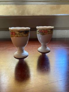 two white cups sitting on top of a wooden table