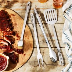 barbecue ribs with bbq sauce and utensils on a wooden board next to beer