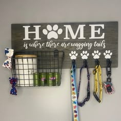 a sign that says home is where there are hugging tails and dogs leashes hanging on the wall