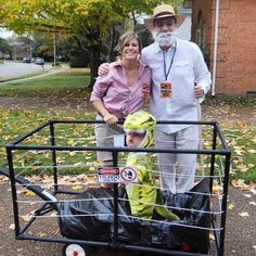 a man and woman standing next to a child in a wagon