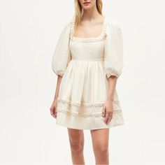 A New Design For Summer, The Daya Dress Is A Mini That Can Be Worn In Many Moods. Made In A Crisp Cotton Poplin, It Has A Flattering Darted Bust And A Full, Flowy Skirt. A Unique Pleated Detail Around The Neck And Towards The Hem Adds A Special Flourish That’s Elegant Without Being Over The Top. 100% Cotton Empire Waist. Hand Wash Cold. Do Not Bleach. Line Dry. Medium Iron. Or Dry Clean. Imported Model Is 5’10” And Is Wearing A Size 2. Elegant Puff Sleeve Dress With Lace Trim For Spring, Cream Square Neck Dress With Lace Trim, Cream Lace Trim Square Neck Dress, Cream Lace Trim Dress With Square Neck, White Puff Sleeve Dress With Lace Trim, Elegant White Puff Sleeve Dress With Lace Trim, Feminine Cream Mini Dress With Square Neck, Cream Mini Dress With Lace Trim For Garden Party, Cream Lace Trim Mini Dress For Garden Party