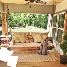 a porch swing with pillows on it