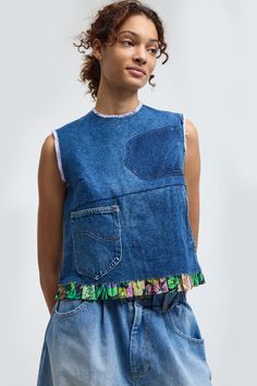 a woman wearing a blue jean jumpsuit with multicolored letters on the side