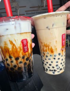 two iced drinks in plastic cups with red straws on the top and black spots on the bottom