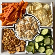 a tray filled with crackers, cucumbers and carrots next to chips