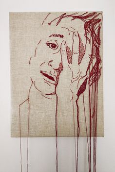 a drawing of a woman holding her hand up to her face with red thread hanging from the wall