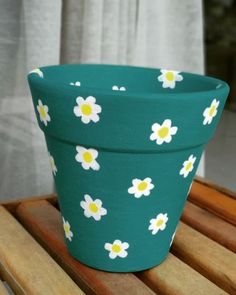 a green flower pot sitting on top of a wooden table