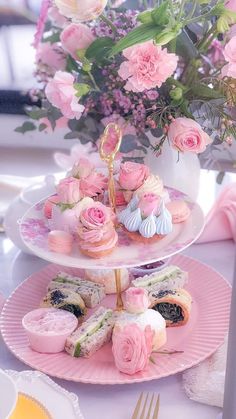 three tiered trays filled with pastries and pink flowers on top of a table