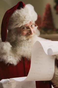 a man dressed as santa claus holding a sheet of paper