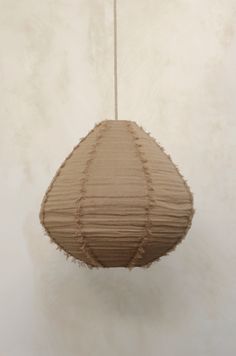 a brown paper lantern hanging from a string on a white wall in the middle of an empty room