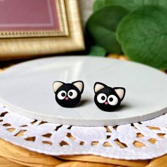 pair of black cat earrings sitting on top of a white plate