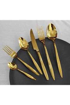 a set of golden forks and spoons on a black plate