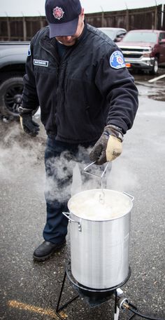 a man in black jacket cooking food on top of a pot with steam coming out of it