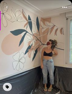 a woman painting a wall with flowers on it