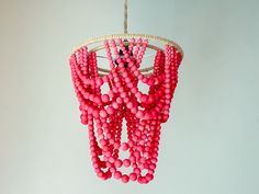 a chandelier with pink beads hanging from it's sides on a white wall