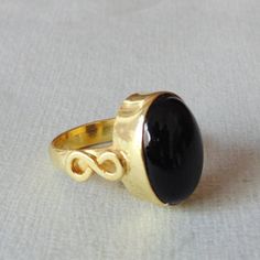 Unique in design, this bezel set statement ring is perfect as a Christmas gift. The handmade beauty with black onyx is a dark stunner. This single gemstone ring is made of brass furnished by 18k gold plating.Product DetailsItem Code: IAJBR- 1391Gross Wt. 7.00 GmsStone Name: Black OnyxMetal: 18K Yellow Gold Plated Over BrassRing Sizes: Please choose from drop down menu. If you do not see your finger size, select custom and I'll make a ring just for you! Shipping Info:All my items are safely and n Black Jewelry With Bezel Setting For Gift, Black Cabochon Ring As A Gift, Black Cabochon Ring For Gift, Black Onyx Ring Gold, Modern Black Cabochon Rings, Onyx Cabochon Round Rings, Oval Cabochon Onyx Ring Gift, Black 14k Gold Cabochon Ring, Onyx Oval Cabochon Rings For Gift