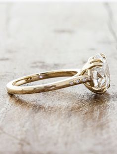 a yellow gold engagement ring with a large diamond in the center on a wooden surface