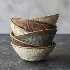 four bowls stacked on top of each other in different shapes and sizes, sitting on a gray surface