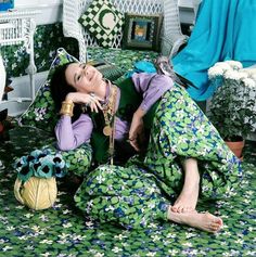 a woman laying on top of a bed covered in green and white bedspreads