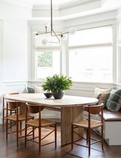 a dining room table with four chairs and a potted plant on the centerpiece