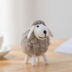 a stuffed sheep sitting on top of a wooden table