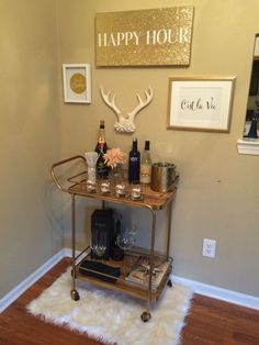 a bar cart with bottles and glasses on it in front of a happy hour sign