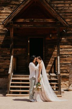 a bride and groom standing in front of a wooden building with steps leading up to it