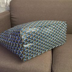 a blue and black pillow sitting on top of a brown couch