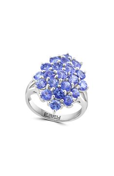 An elegant setting of tanzanite stones brings vibrant sparkle to this sterling silver ring and adds a glamorous finish to any outfit. 7/8"W x 3/4"L setting Total tanzanite weight: 3.59ct. Sterling silver/tazanite Made in the USA Tanzanite Engagement Ring, Silver Flower Ring, Yellow Gemstones, Tanzanite Ring, Ring Pendant Necklace, Sterling Silver Flowers, Flower Ring, Cluster Ring, Tanzania