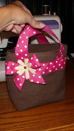 a hand is holding a pink and brown bag with white polka dots on the side