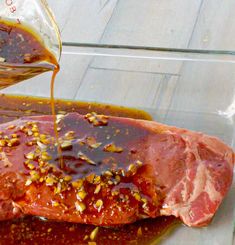 a piece of meat is being poured on top of some sauce in a glass dish