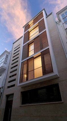 an apartment building with balconies on the second floor and windows above it at dusk