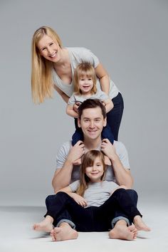 a man, woman and child sitting on top of each other in front of a gray background