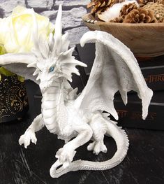 a white dragon figurine sitting on top of a table next to some flowers